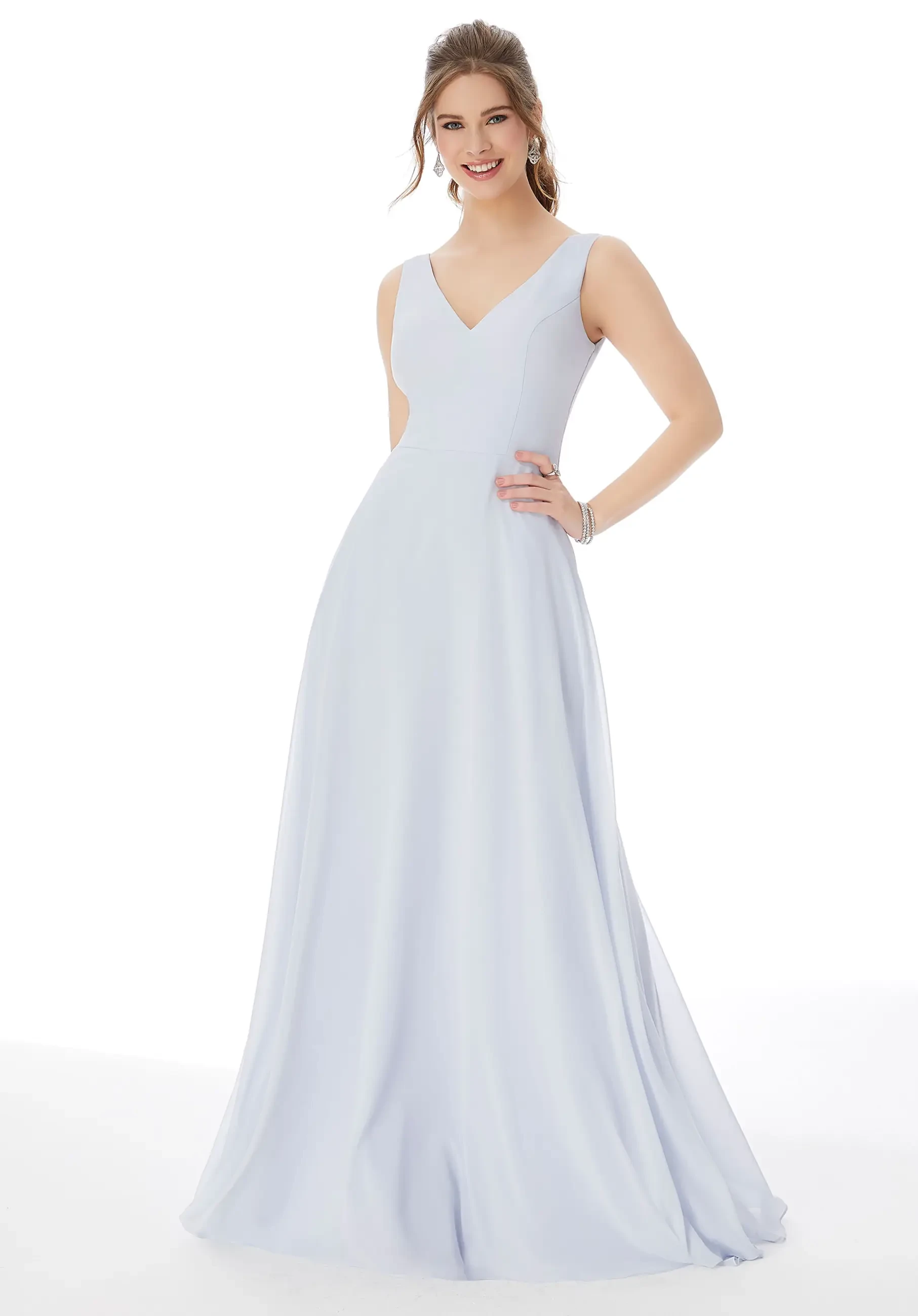 A woman is wearing a light blue, sleeveless dress with a V-neckline, posing confidently.