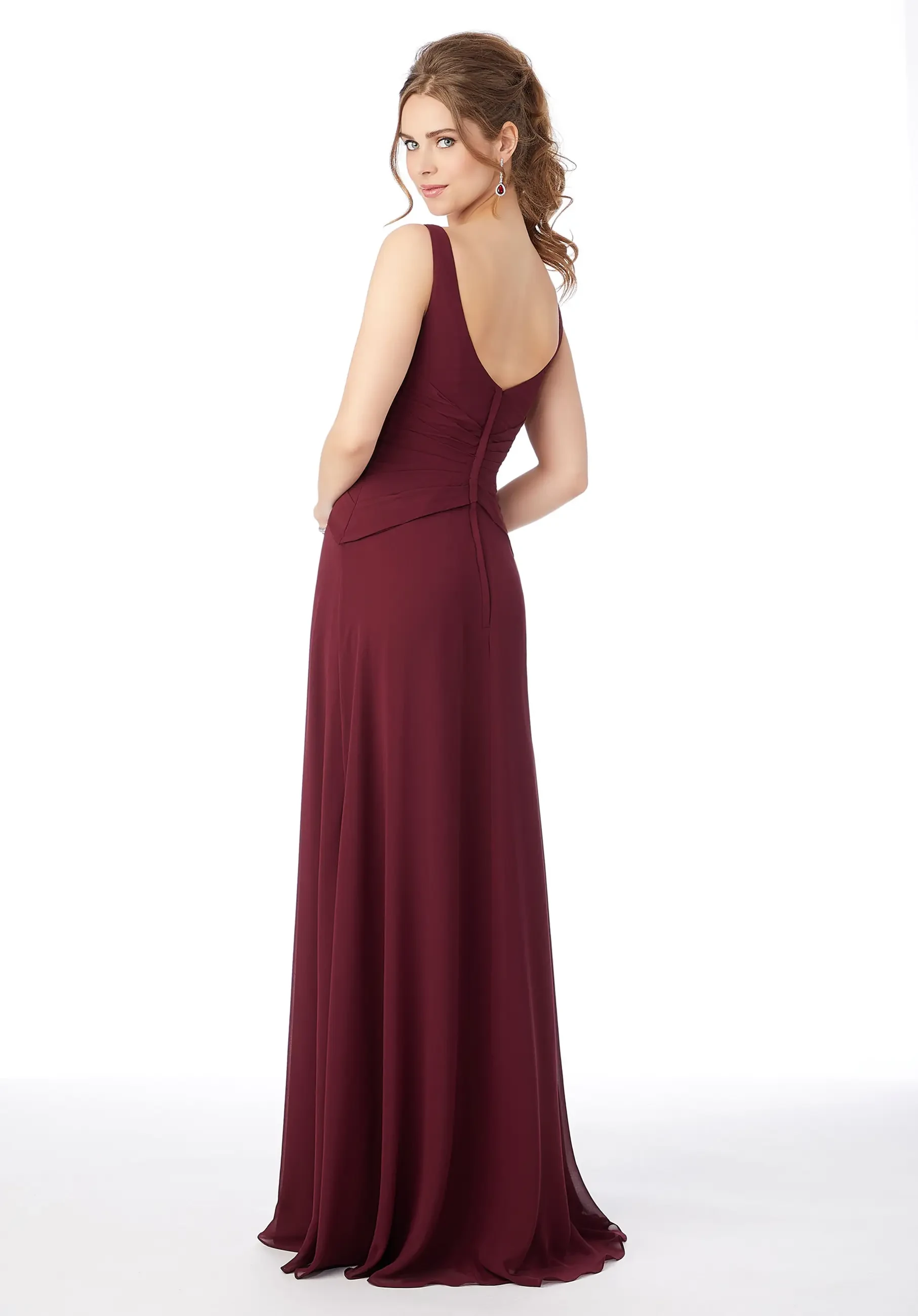 A woman is wearing a sleeveless burgundy dress, standing with her back to the camera, showing the dress's flowing design.