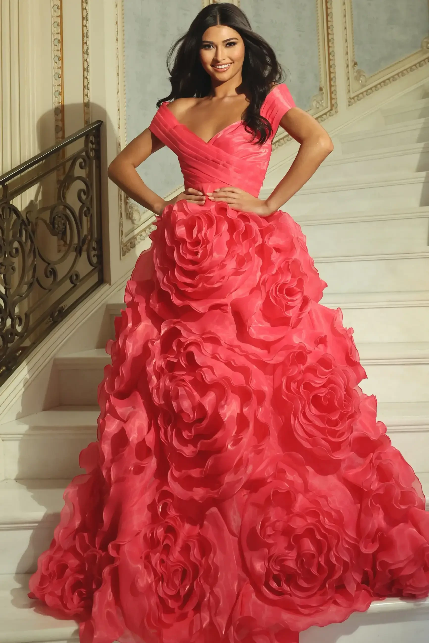 model is wearing an off the shoulder coral ball gown prom dress