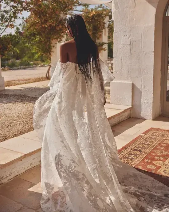 model is wearing an off the shoulder a-line wedding dress