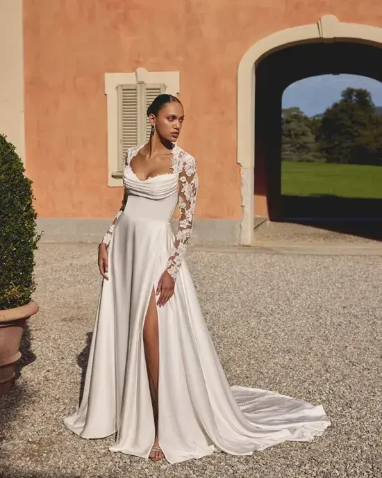 Model is wearing a charmeuse A-line wedding gown with a Queen Anne neckline and corded Alençon lace detailing on the back.
