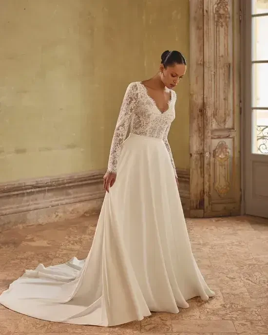 Model is wearing a fit-and-flare wedding gown with allover corded Alençon lace and a keyhole back.\
