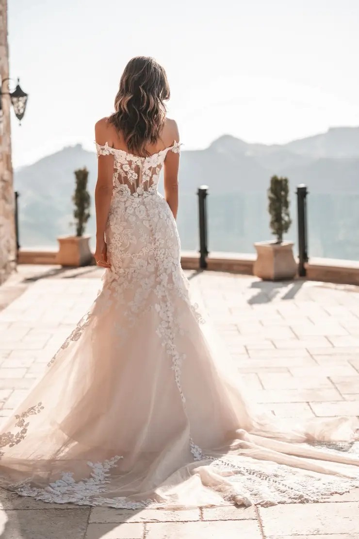 Model is wearing a sparkly wedding dress with off the shoulder sleeves by allure bridals
