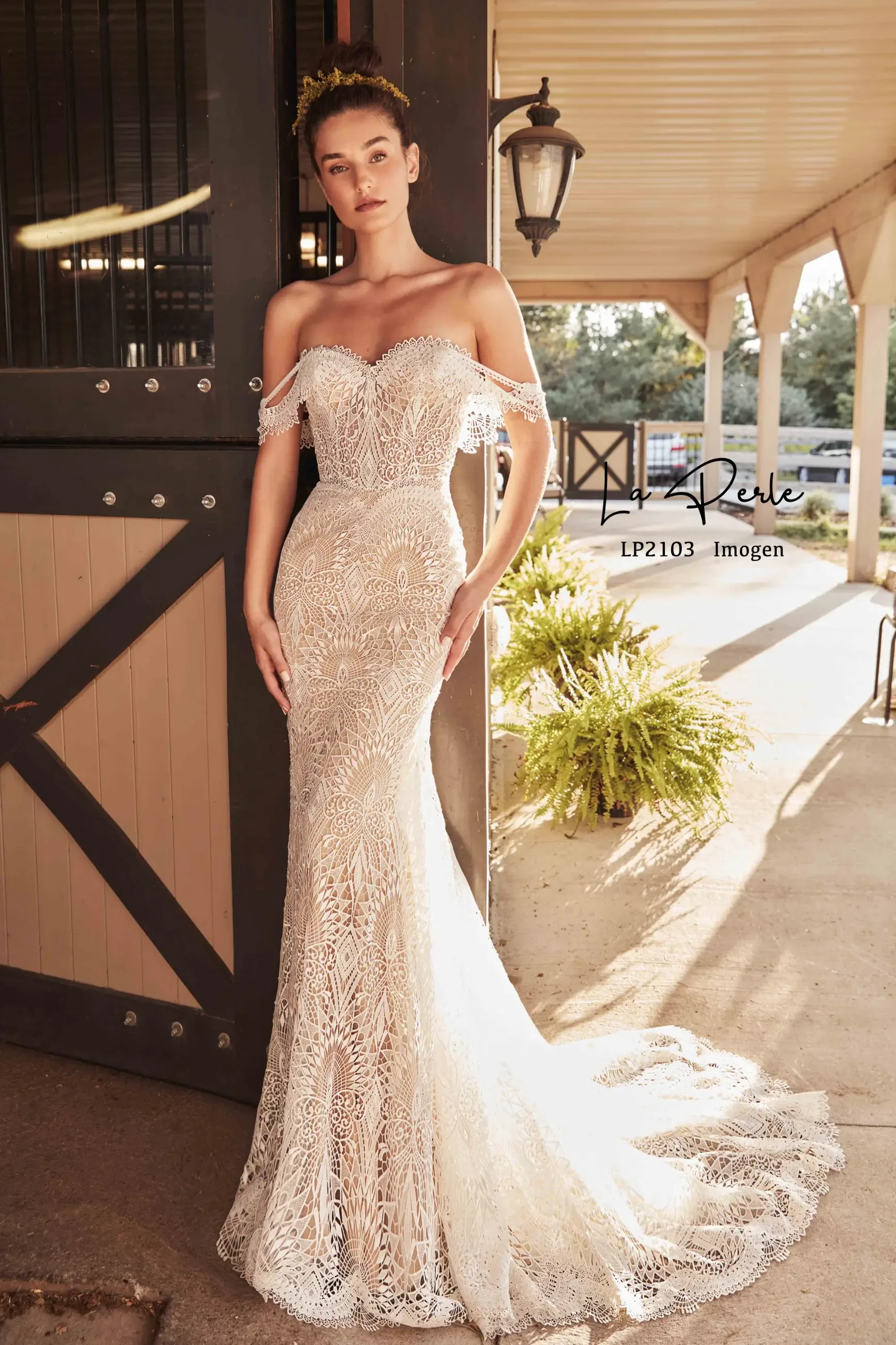 Model is wearing a romantic fit-and-flare gown with delicate lace, an off-the-shoulder neckline, and a dramatic train.