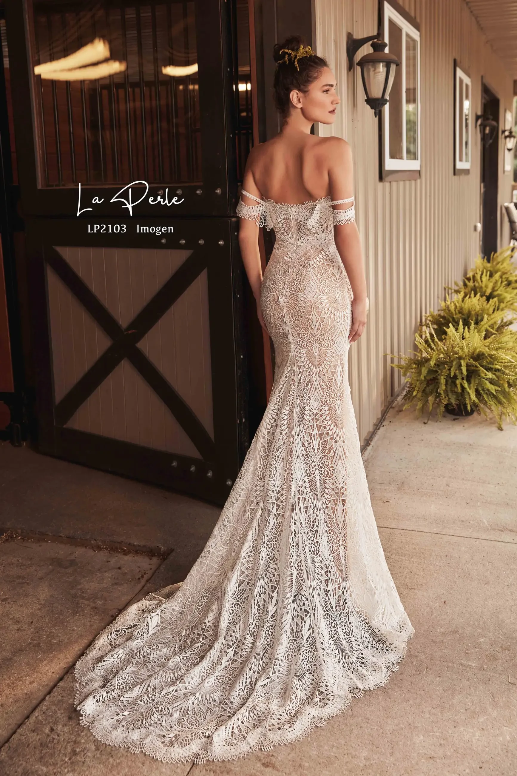 Model is wearing a romantic fit-and-flare gown with delicate lace, an off-the-shoulder neckline, and a dramatic train.