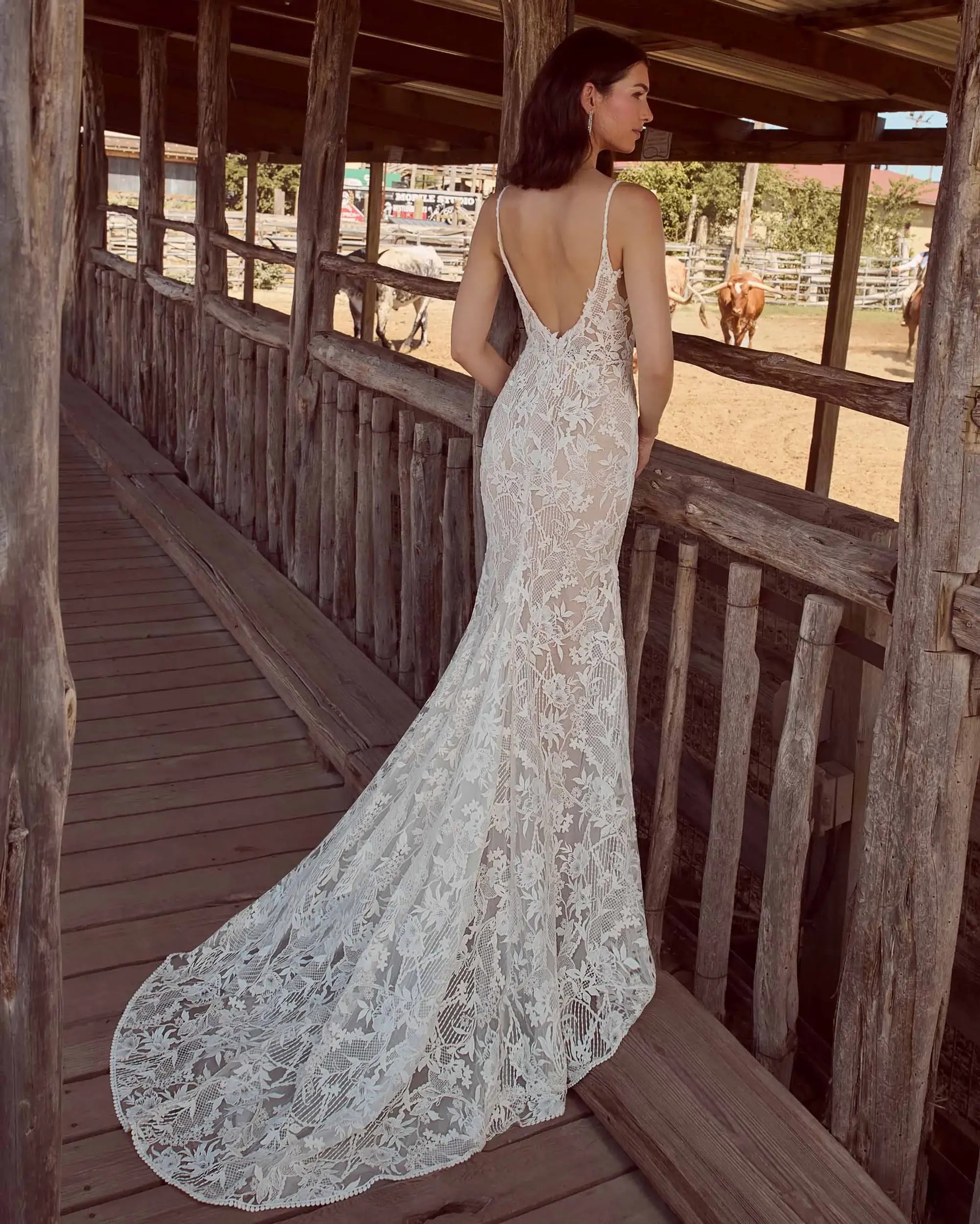 Model is wearing a lace wedding dress with spaghetti straps and an open back 