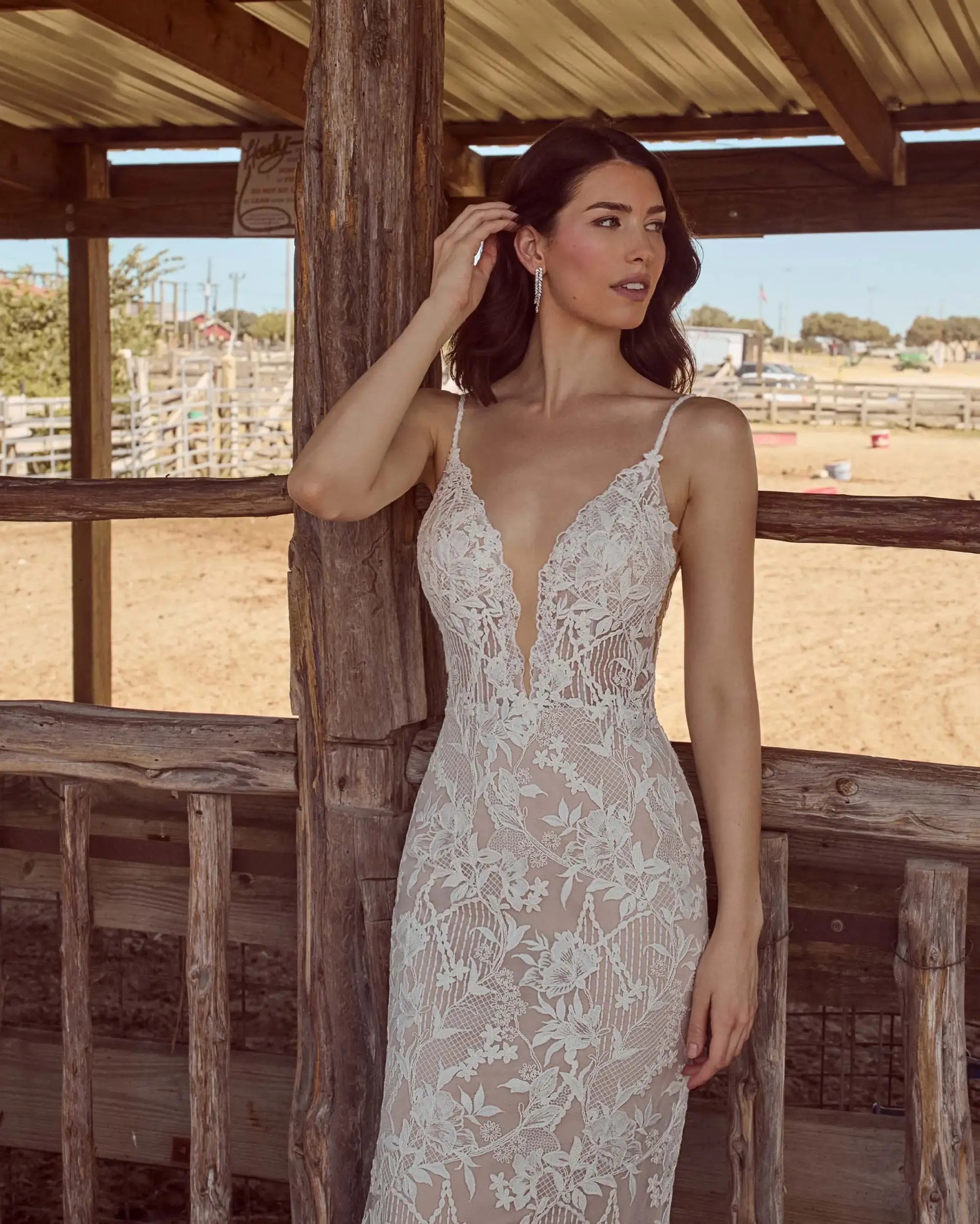 Model is wearing a lace wedding dress with spaghetti straps and an open back 