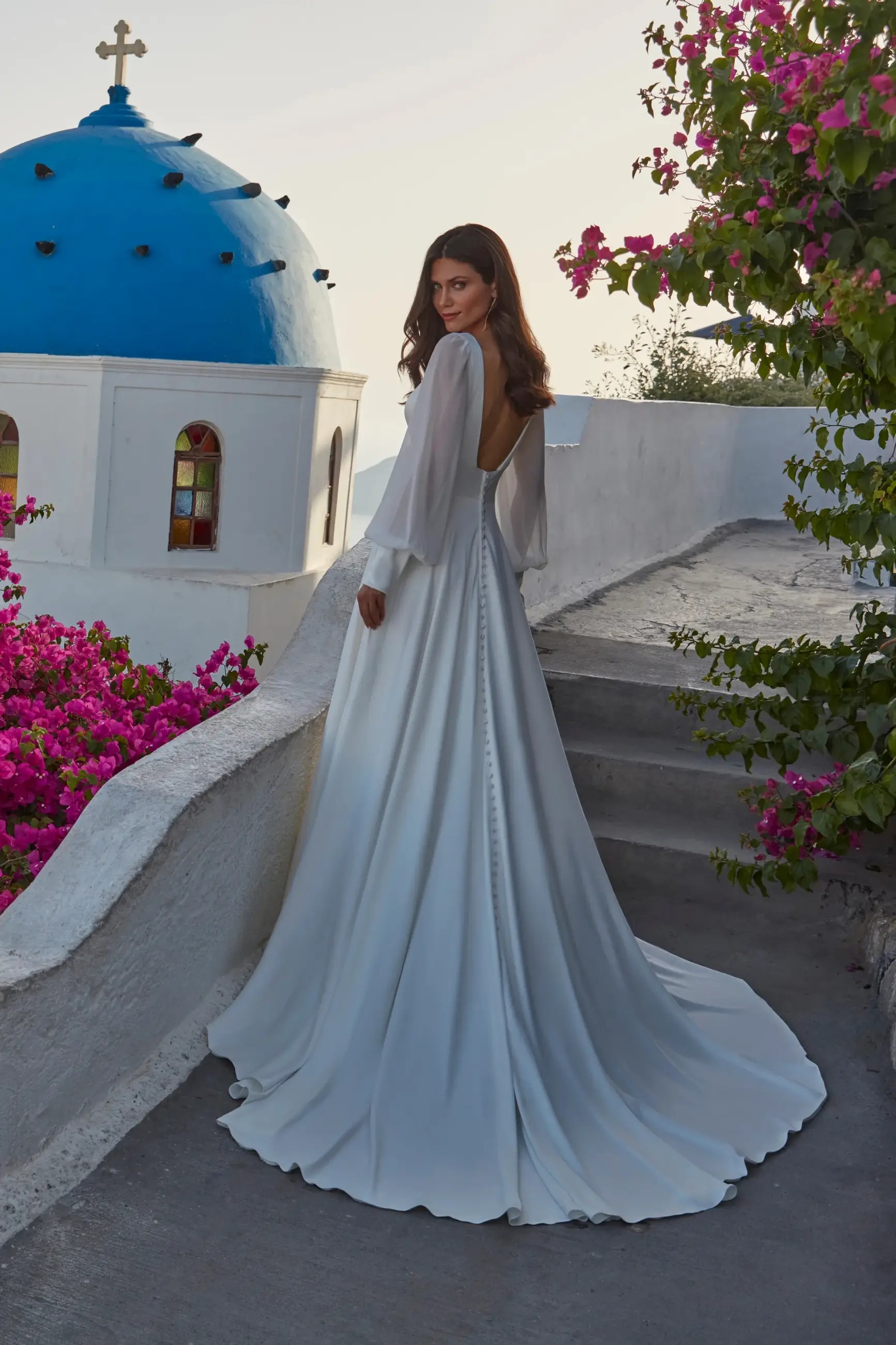 Model is wearing a satin a-line bridal gown with chiffon bishop sleeves by madison james